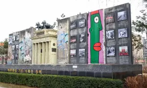 Fragment muru berlińskiego z graffiti i zdjęciami upamiętniającymi historię podzielonych Niemiec.