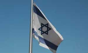 Flaga Izraela powiewa na wietrze na tle błękitnego nieba.
