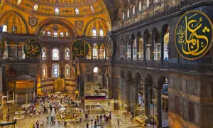 Wnętrze Hagia Sophia z wielkimi okrągłymi kaligrafiami, kopułą i tłumem turystów.