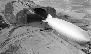Ogromny hangar lotniczy i sterowiec Hindenburg na płycie lotniska.