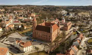 Zamek w Lidzbarku Warmińskim, jedna z głównych atrakcji, otoczony wodą i malowniczym miastem.