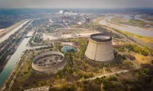 Widok na opuszczoną elektrownię atomową, gdzie doszło do katastrofy w Czarnobylu. Widać niedokończone wieże chłodnicze i rozległy teren.