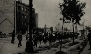 Żołnierze maszerują ulicą. Obraz przypomina o tym, ile trwało powstanie warszawskie.