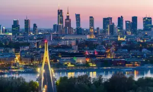 Warszawa nocą, z mostem i wieżowcami. Miasto tętni życiem, a jego warszawa liczba mieszkańców stale rośnie.