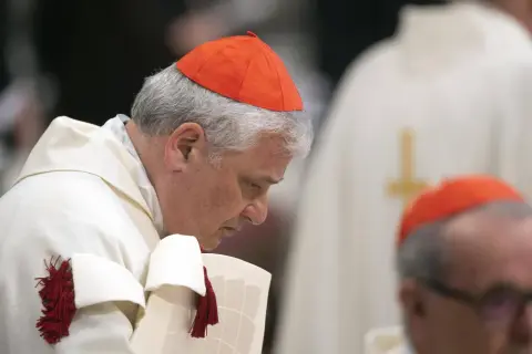 Dwóch kardynałów polskich w czerwonych biretach i białych szatach. Jeden pochyla się nad dokumentem.