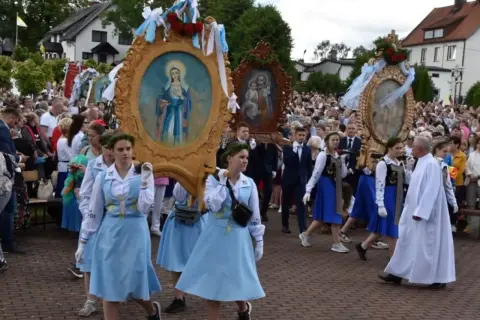 Procesja niesie ozdobne feretrony z obrazami Matki Bożej i Świętej Rodziny. Tłum ludzi towarzyszy niesionym feretronom.