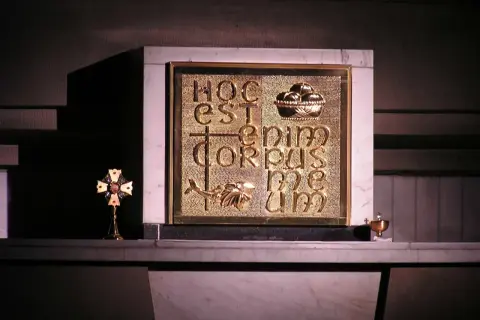 Złote tabernakulum z napisem "Hoc est enim corpus meum" i symbolem ryby. Obok krzyż relikwiarzowy.