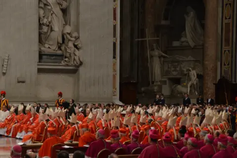 Wielu kardynałów w szatach liturgicznych, zastanawiających się, kto może zostać papieżem.