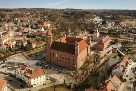 Zamek w Lidzbarku Warmińskim, jedna z głównych atrakcji, otoczony wodą i malowniczym miastem.