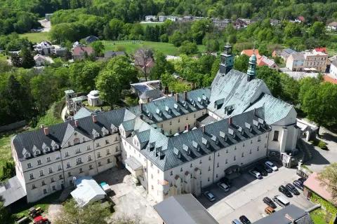 Widok z lotu ptaka na klasztor na Górze Świętej Anny. Rozległy kompleks budynków z zielonymi dachami otoczony bujną zielenią.