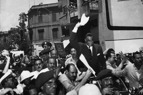 Gamal Abdel Nasser, drugi prezydent Egiptu, pozdrawia tłum z otwartego samochodu.