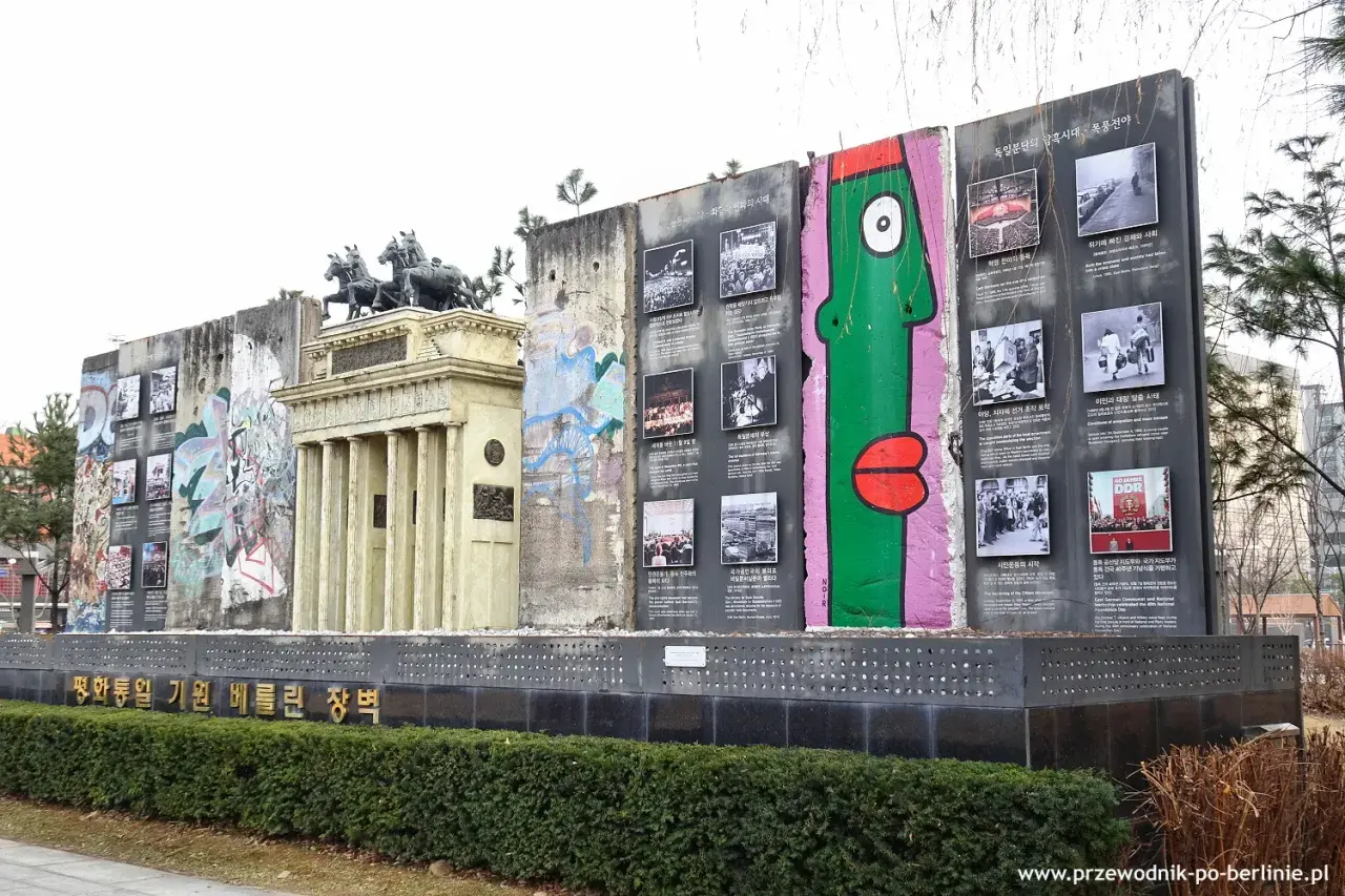 Fragment muru berlińskiego z graffiti i zdjęciami upamiętniającymi historię podzielonych Niemiec.