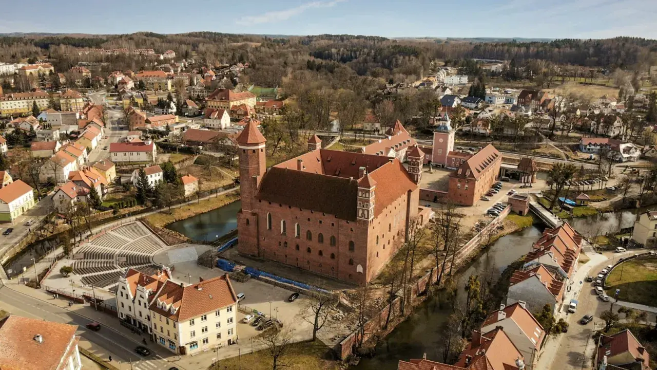 Zamek w Lidzbarku Warmińskim, jedna z głównych atrakcji, otoczony wodą i malowniczym miastem.