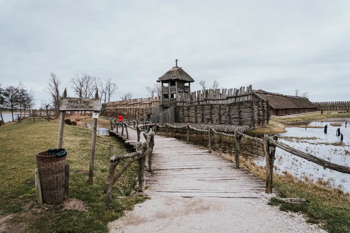Drewniana osada obronna, wieża strażnicza i palisada. Mostek prowadzi do wnętrza grodu, który jest częścią szlaku piastowskiego.
