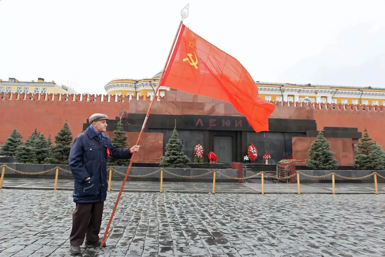 Starszy mężczyzna z czerwoną flagą przed mauzoleum Lenina.