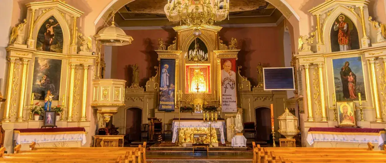 Wnętrze kościoła z ołtarzem głównym, obrazami świętych i tabernakulum.