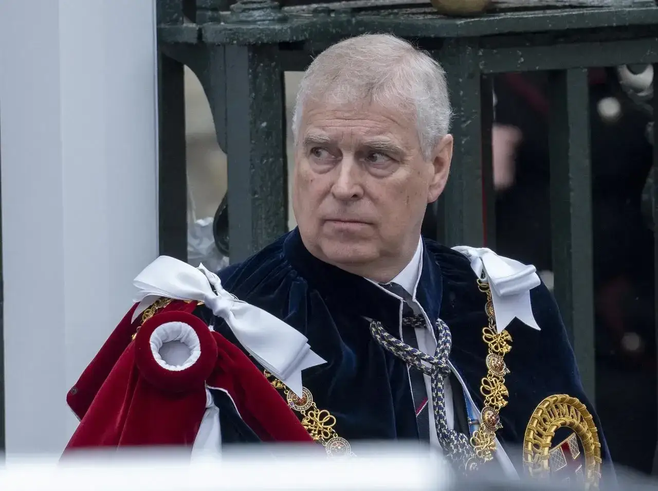 Książę Andrzej w uroczystym stroju, z aksamitnym płaszczem i złotymi ozdobami, wygląda na zamyślonego.