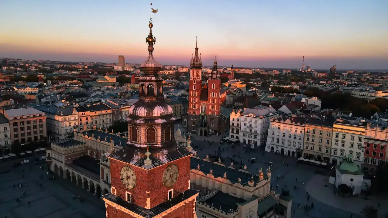 Zachód słońca nad Rynkiem Głównym w Krakowie. Wieża Ratuszowa i Kościół Mariacki w blasku złotego światła. Ciekawe ciekawostki o Krakowie czekają na odkrycie!