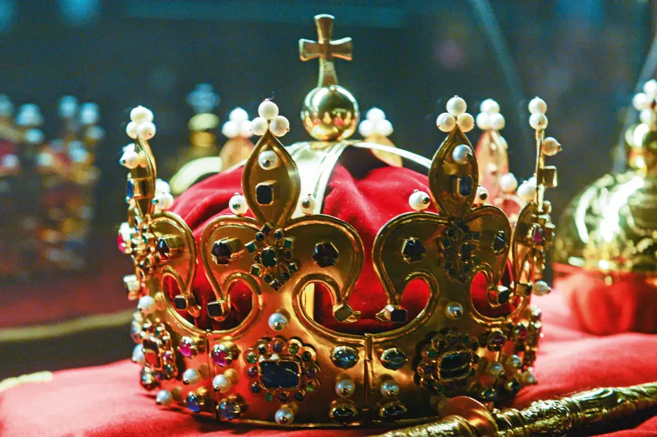 Złota korona ozdobiona perłami i klejnotami, symbol władzy i dziedzictwa. Wyobraź sobie, że to korona młodego księcia, który wkrótce obejmie tron.