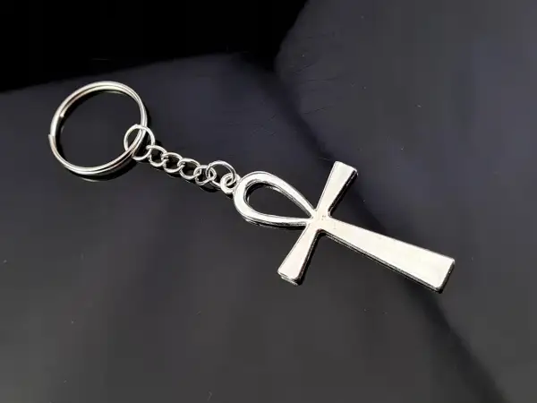 Srebrny brelok z symbolem ankh, starożytnym egipskim znakiem życia, na czarnym tle.
