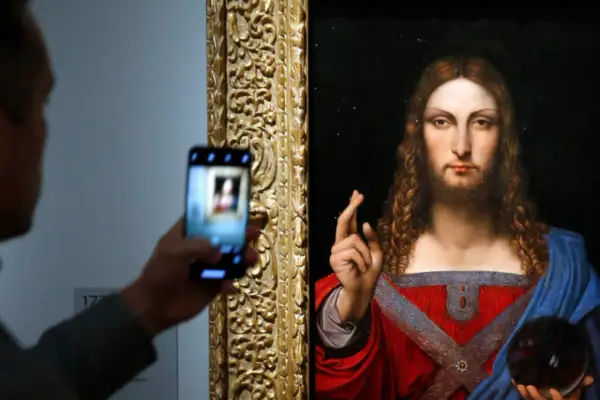 Osoba robi zdjęcie telefonem komórkowym obrazu "Salvator Mundi" przedstawiającego Jezusa.
