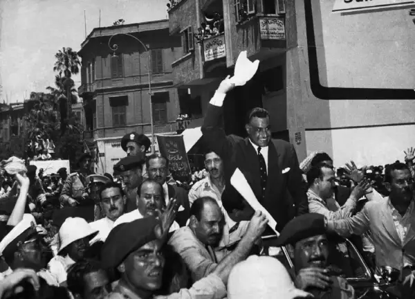 Gamal Abdel Nasser, drugi prezydent Egiptu, pozdrawia tłum z otwartego samochodu.
